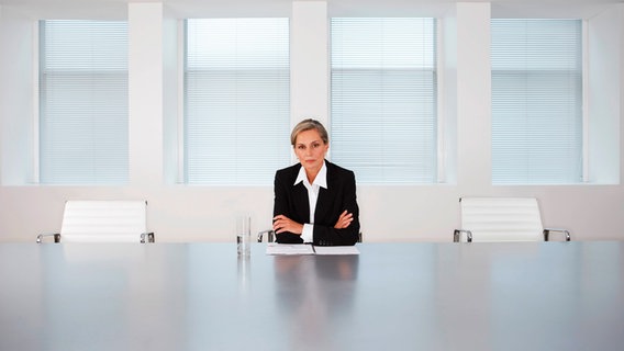 Eine Frau sitzt alleine an einem großen Tisch. © NDR 