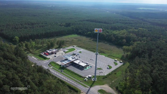 Blick aus der Vogelperspektive auf ein kleineres Gewerbegebiet mit Parkplatz inmitten eines riesigen Waldareals. © Screenshot 