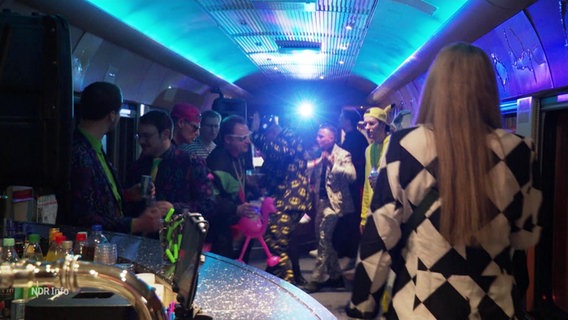 Personen, kostümiert, in einem Zugabteil mit Partybeleuchtung © Screenshot 