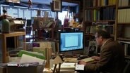 Gerd Stechen sitzt in seiner Buchhandlung am Computer. © Screenshot 