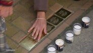 Eine Hand streicht über Stolpersteine in Stralsund. © Screenshot 