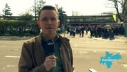 Reporter Heiko Sanders berichet live vor Ort, im Hintergrund das Millerntorstadion und St. Pauli Fans. © Screenshot 