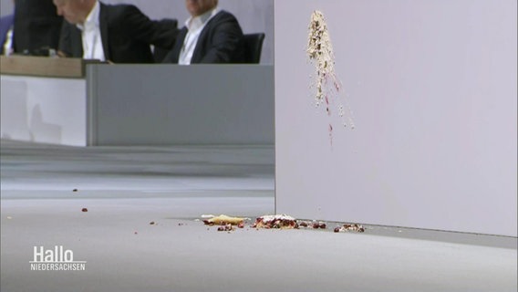 Ein Kuchen wurde von Aktivist:innen auf einer Veranstaltung von Porsche auf die Bühne geschmissen. © Screenshot 