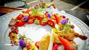 Bunter Spargelsalat mit Erdbeeren und Blumen dekoriert. © Screenshot 
