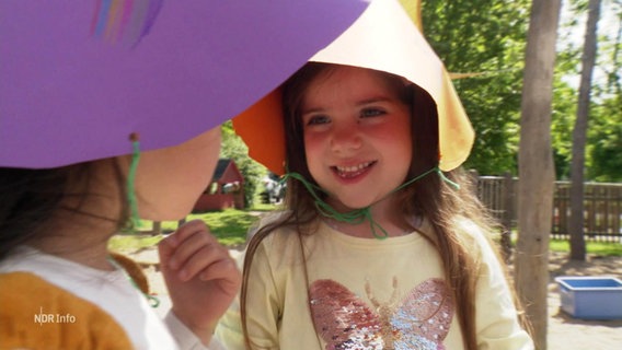 Children wear self-made sun hats made of colorful cardboard.  ©Screenshot 