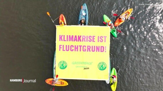 Kayaks im Wasser, Menschen darin halten ein Banner auf dem "Klimakrise ist Fluchtgrund" steht © Screenshot 