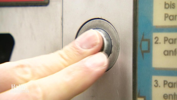 Zwei Finger drücken auf einen Parkscheinautomatenknopf. © Screenshot 