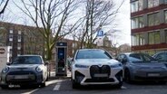 Mehrere E-Autos stehen in einer Reihe nebeneinander und laden an einer Ladesäule am Straßenrand. © Screenshot 