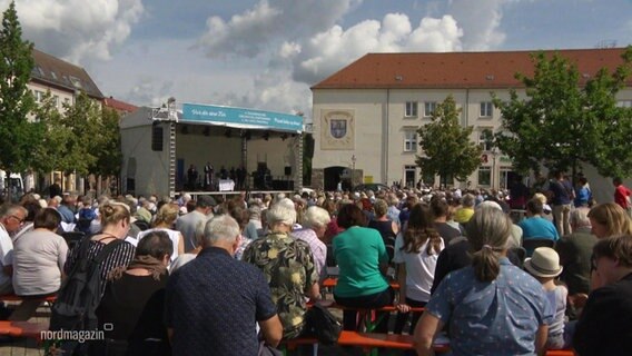 Viele Menschen sitzen bei einem Open Air Gottesdienst vor einer Bühne. © Screenshot 