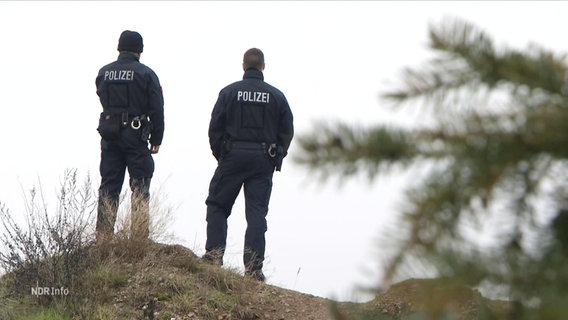Zwei Polizeibeamte stehen auf einem Hügel. © Screenshot 