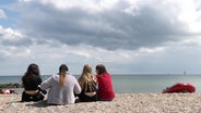 Vier Jugendliche sitzen am Ostseestrand und blicken aufs Meer. © Screenshot 