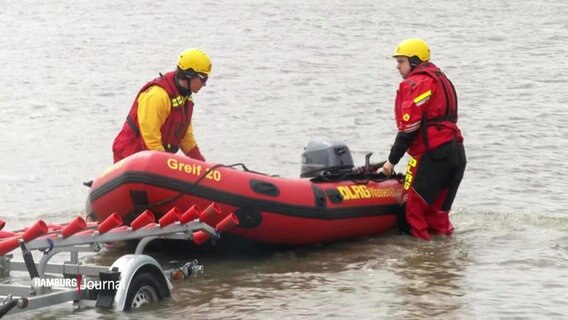 Zwei Mitarbeiter der DLRG lassen ein Schlauchboot zu Wasser. © Screenshot 