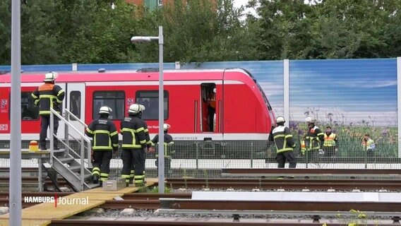 Feuerwehrleute leiten Menschen aus einer liegen gebliebenen S-Bahn. © Screenshot 
