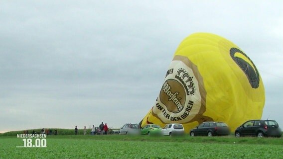 Ein in sich zusammengefallener Heißluftballon liegt auf einem Feld. © Screenshot 