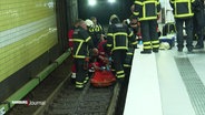Einsatzkräfte der Feuerwehr retten einen Mann aus einem Gleisbett. © Screenshot 
