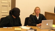 Ein Angeklagter hat vor Gericht sein Gesicht mit einem schwarzen Tuch verhüllt. © Screenshot 