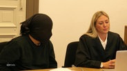 Der Angeklagte mit schwarzer Strumpfmaske im Gerichtssaal. © Screenshot 