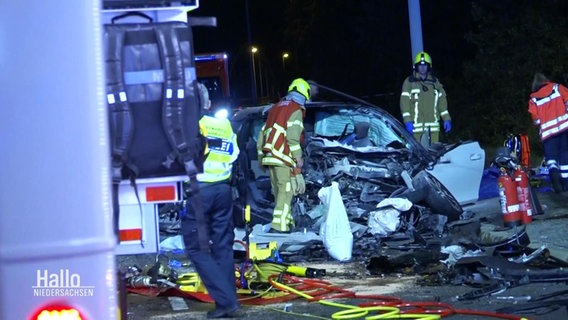 Rettungskräfte stehen neben einem Unfallauto. © Screenshot 