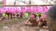 Frauen kriechen im Schlamm durch einen Hindernisparcours. © Screenshot 