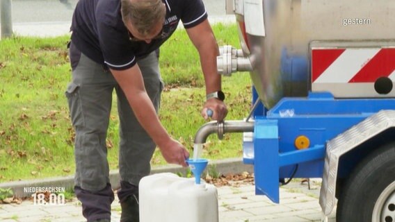 Ein Mann füllt Wasser aus einem Tank in einen Kanister. © Screenshot 
