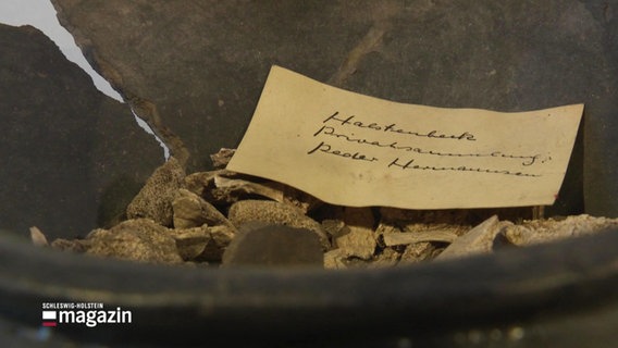 Eine 3.500 Jahre alte Urne mit einem Zettel in Nahaufnahme © Screenshot 
