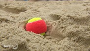 Ein Tennisball liegt im feinen Sand. © Screenshot 