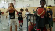 Kinder mit Basketbällen in einer Sporthalle. © Screenshot 