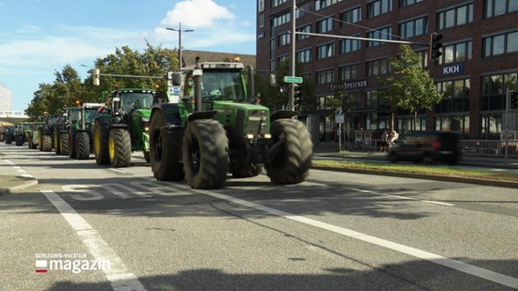 Mehrere Traktoren rollen eine größere Straßen in einer Stadt in einer Kolonne entlang. © Screenshot 