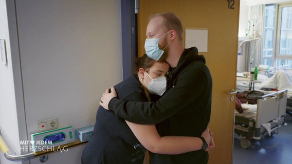Eine Frau und ein Mann umarmen sich im Flur eines Krankenhauses. © Screenshot 