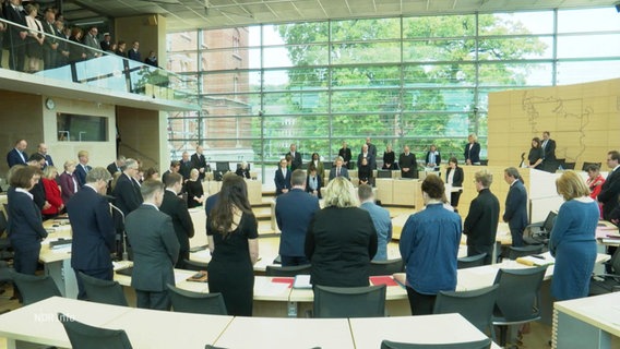 Menschen stehen zu einer Schweigeminute im Schweriner Landtag. © Screenshot 