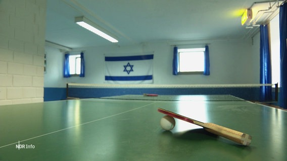Hinter einer Tischtennisplatte hängt die Fahne Israels. © Screenshot 