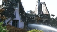 Ein abgebranntes Haus wird von der Feuerwehr gelöscht. © Screenshot 