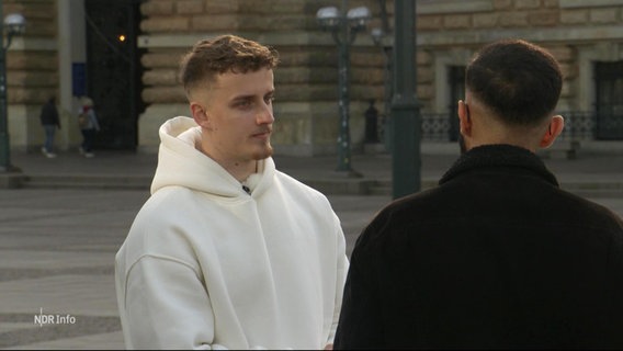 Zwei junge Männer unterhalten sich auf der Straße. © Screenshot 
