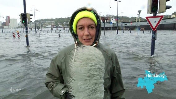 Reporterin Simone Mischke steht vor überfluteten Straßen in Flensburg. © Screenshot 