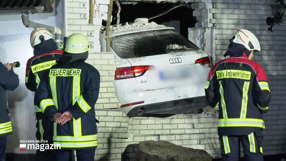 Feuerwehrleute stehen vor einem Haus. Ein Auto ist in das Haus gefahren, hat die Mauern zerstört. © Screenshot 