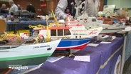 Schiffsmodelle stehen auf einer Modellbaubörse aufgereiht nebeneinander. © Screenshot 