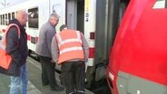 Drei Bahnbeamte betrachten die Verbindung zwischen Lok und Waggons. © Screenshot 