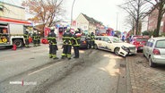 Auf einer mehrspurigen Straße sind Rettungskräfte der Feuerwehr dabei eine Unfallstelle mit mehreren Fahrzeugen, unter anderem ein Taxi, abzusichern. © Screenshot 