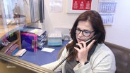 Eine Frau an einem Empfangstresen am Telefon. © Screenshot 