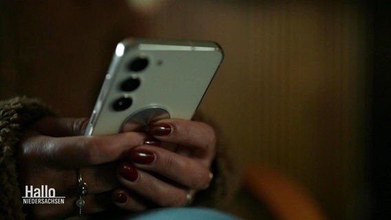 Nahaufnahme der Hände einer Frau, die ein Smartphone hält. © Screenshot 