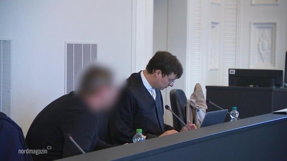 Eine Anklagebank in einem Gericht, der Angeklagte ist verpixelt zu sehen. © Screenshot 