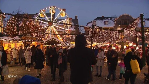 Szenerie auf einem Weihnachtsmarkt mit Lichterketten, Riesenrad und Essensständen. © Screenshot 