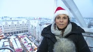 Tatjana Brand sitzt im Riesenrad mit dem Rostocker Weihnachtsmarkt im Hintergrund. © Screenshot 
