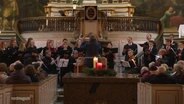 In einer Kirche singen junge Menschen in einem Chor bei einem Konzert. © Screenshot 