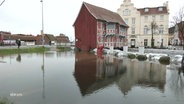 Gebäude die im Wasser stehen und aufgetürmte Sandsäcke. © Screenshot 