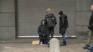Die Sozialarbeiterin Sarah Menn und ihre Kollegin sprechen einen bettelnden Mann auf der Straße an, der am Boden kniet. © Screenshot 