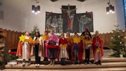 Sternensinger in einer Kirche, die noch weihnachtlich geschmückt ist. © Screenshot 