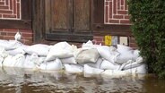 Sandsäcke vor der Haustür eines Fachwerkhauses, das Wasser erreicht schon fast die Türschwelle. © Screenshot 