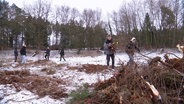 Schülerinnen und Schüler arbeiten gemeinsam im verschneiten Moor und sammeln Zweige und Äste ein. © Screenshot 