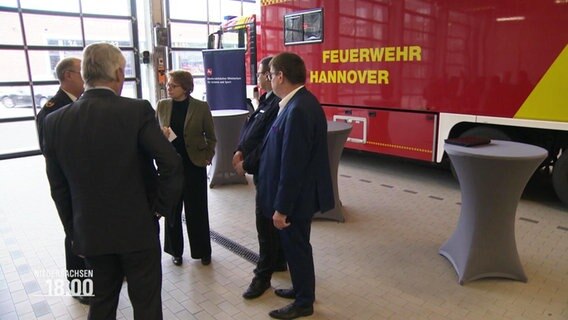 Die niedersächsische Innenministerin Daniela Behrens von der SPD unterhält sich mit mehreren Personen vor einem Einsatzfahrzeug der Feuerwehr Hannover. © Screenshot 